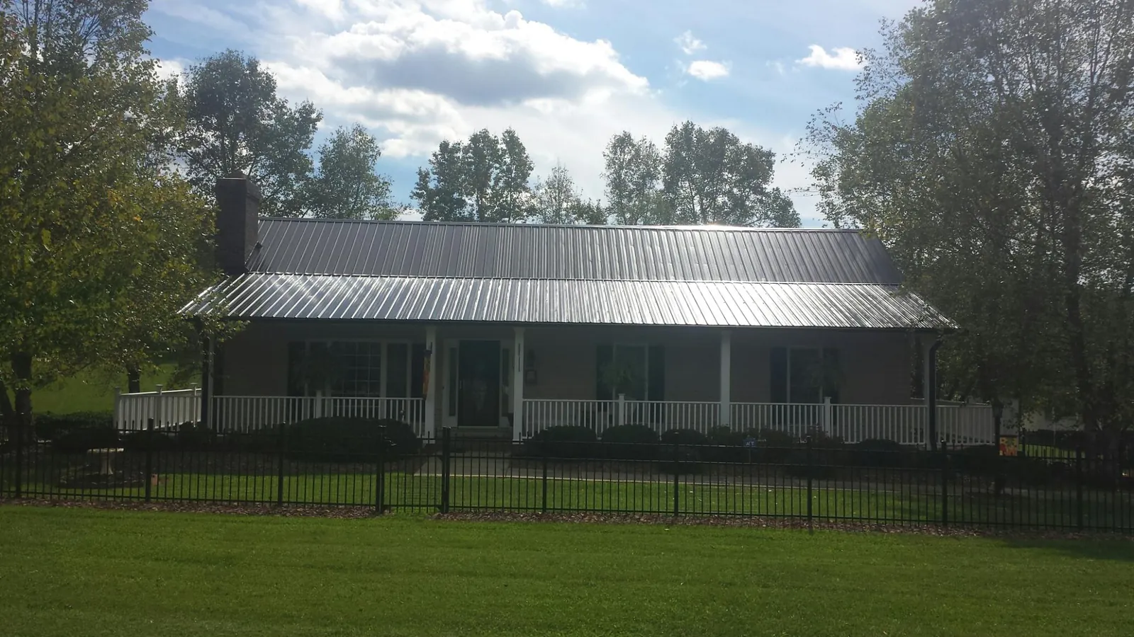 Gray metal roof on a brick ranch with a full width front porch — Gutter Guard Installation work by our crew in Ararat