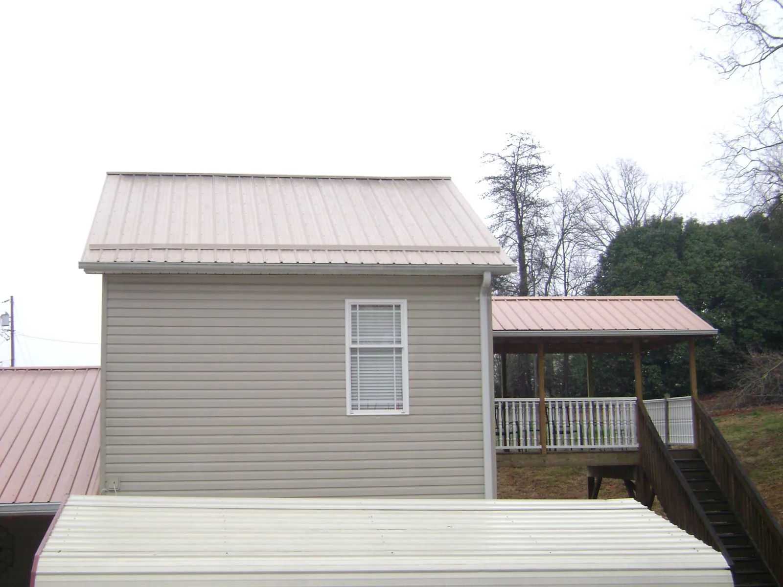 Tan metal roofs on a two story addition and attached porch, from a Roof Replacement job in Ararat